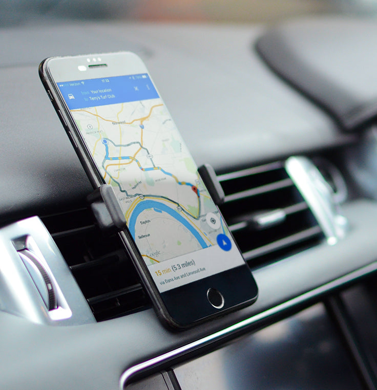 An Apple iPhone showing navigation, cradled in a vent mount in car holder on a dashboard of a premium car